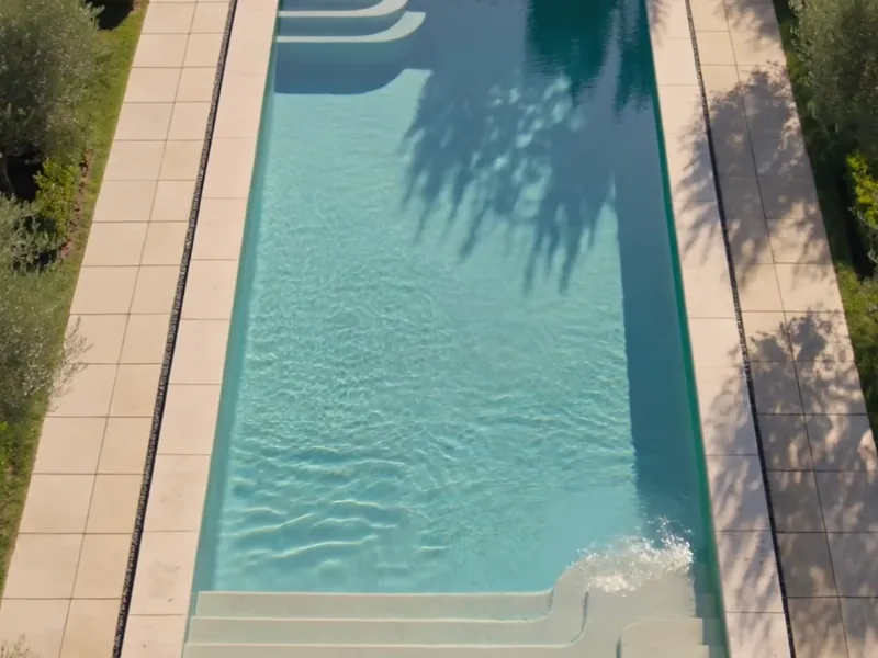 Piscine terminée, eau claire, plage en pierre et oliviers